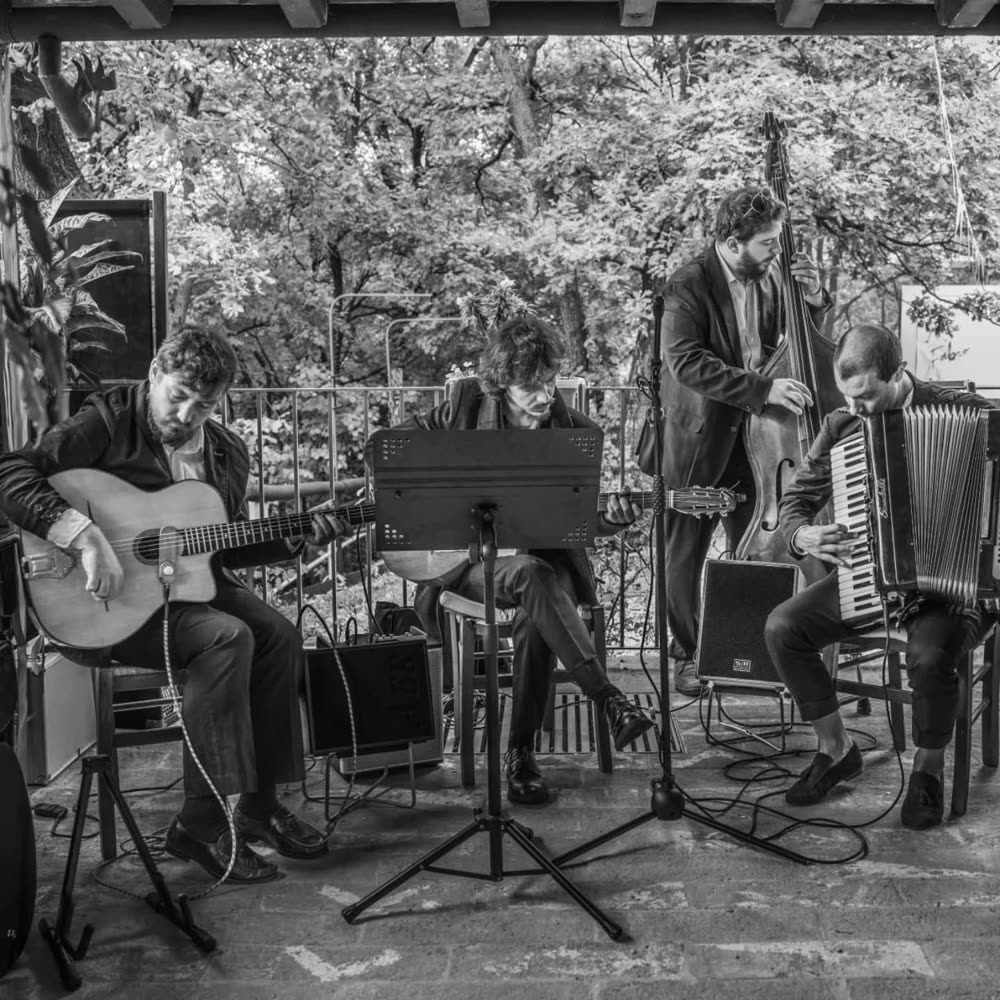 Il quartetto durante un concerto, in bianco e nero: chitarra, contrabbasso e fisarmonica